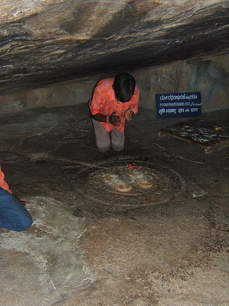 Джайнский пилигрим кланяется стопам святого Бхадрабаху. Чандрагупта Маурья поклонялся этим стопам своего учителя и принял в этой пещере добровольную смерть от длительного поста.