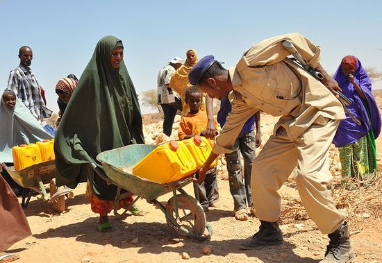 Сомалилендский полицейский помогает женщине в перевозке воды